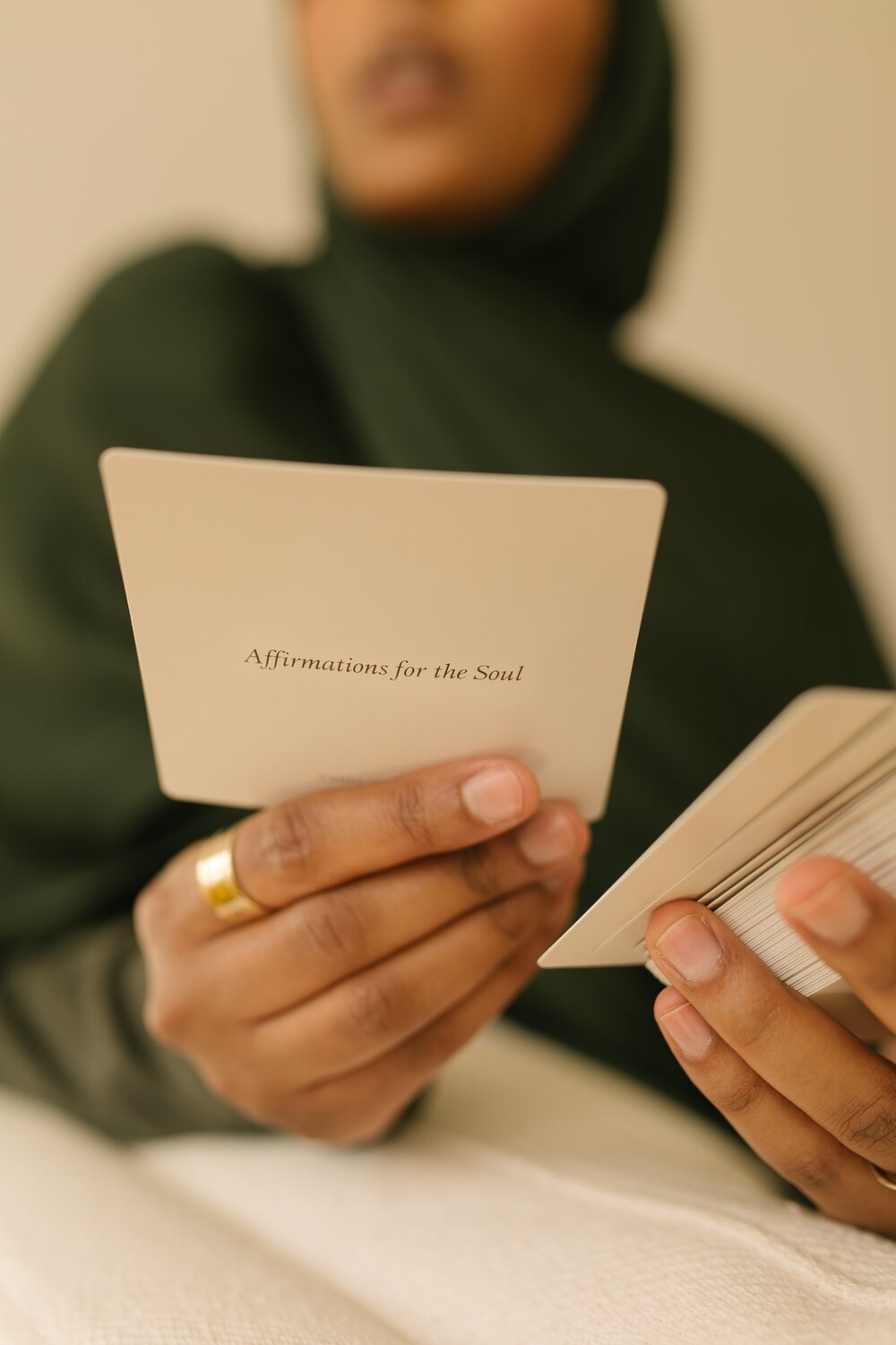 A muslim woman holding a card from Chinutay & Co's Affirmations for the Soul.